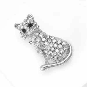 Détails d'une broche chat argentée ornée de strass brillants et yeux en gemmes noires