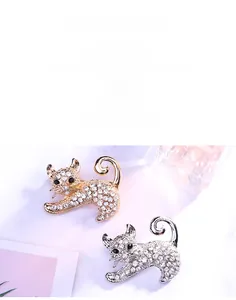 Détail de broches chat or et argent avec strass scintillants sur surface texturée