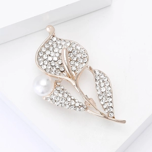Détail de la broche feuille avec strass brillants et une grande perle blanche élégante