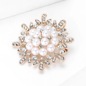 Detailed view of a gold snowflake brooch with white pearls and sparkling rhinestones