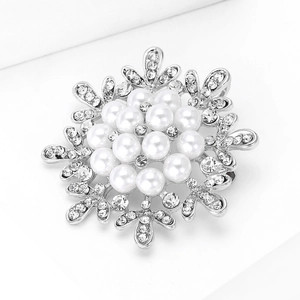 Close-up of snowflake brooch with silver metal, white pearls and sparkling rhinestones
