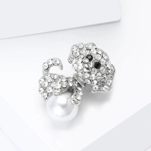 Detail van de hondenspeld met witte strassteentjes en een grote witte parel op zilver