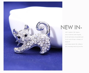 Gros plan d'une broche chat argentée avec strass blancs et yeux noirs sur velours bleu