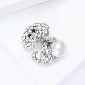 Macro-opname van zilveren puppy-broche met witte strasstenen en een parel op een witte stand