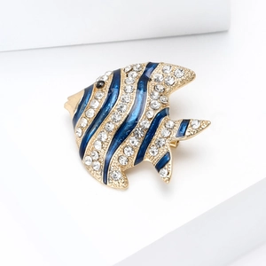 Macro detail of blue enamel fish brooch with sparkling rhinestones and gold plating
