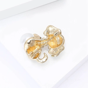 Detailopname achterkant van een gouden broche met veiligheidsspeld en ronde parel