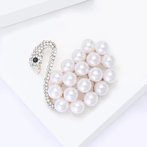 Broche cygne dorée avec perles blanches et cristaux brillants sur fond épuré