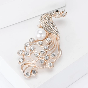Elegante spilla a pavone dorata con strass scintillanti e una grande perla bianca tonda