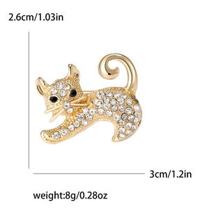 Broche chat dorée avec des strass blancs et des yeux en pierres noires sur fond blanc