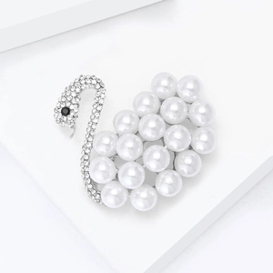 Détail macro d'une broche cygne avec perles blanches et oxydes de zirconium brillants