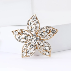 Elegant gold flower brooch with sparkling crystals on a minimalist white display