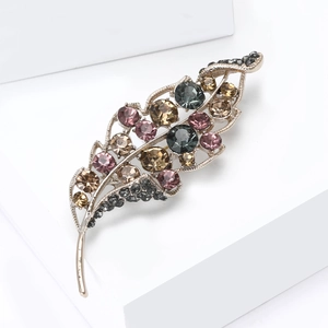 Elegant leaf brooch with multi-color rhinestones on a minimalist white background
