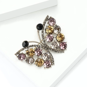 Macro detail of butterfly brooch showing multicolored rhinestones on a metal base