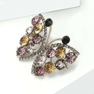 Macro detail of alloy butterfly brooch with vibrant rhinestones on white pedestal