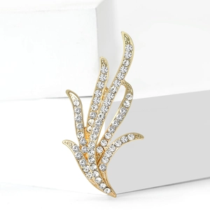 Élégante broche feuille de narcisse dorée avec cristaux blancs sur un socle blanc