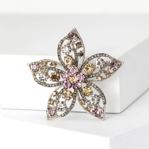 Detail of silver flower brooch with pink, champagne and clear rhinestones on white base