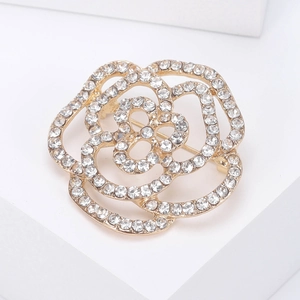 Elegante spilla a fiore dorata con strass scintillanti su un piedistallo bianco puro