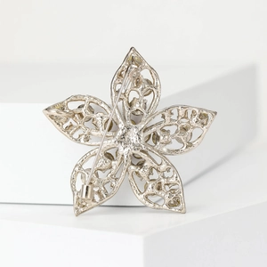 Macro shot of silver hollow floral brooch with pin fastening on geometric block