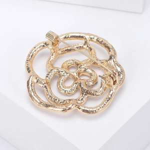 Elegante spilla a fiore traforato dorata con strass su supporto da esposizione