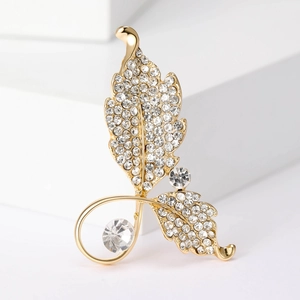 Élégante broche feuille dorée avec strass et perles sur support blanc géométrique