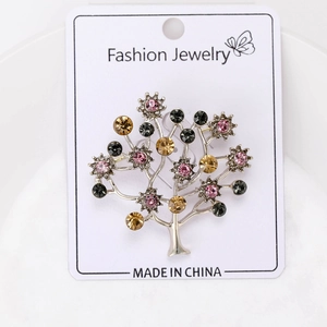 Detailed view of tree-shaped brooch with multi-color rhinestones on silver metal base