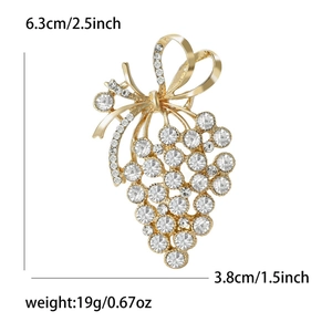 Elegante spilla a uva dorata con strass scintillanti e fiocco su sfondo bianco
