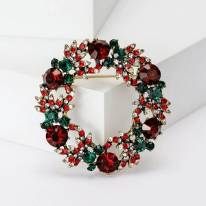 Detalle del broche de corona de Navidad con cristales rojos y verdes sobre base dorada