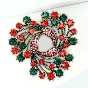 Macro shot of vintage bronze swirl brooch with red and green rhinestones and AB crystal detail