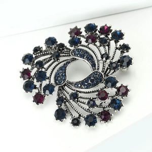Detailed close-up of a vintage silver brooch with navy blue and purple rhinestones