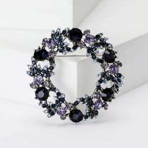 Detalle del broche de corona navideña con cristales azul profundo y violetas