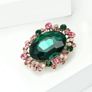 Macro detail of vintage brooch with green oval crystal and pink rhinestones on bronze base