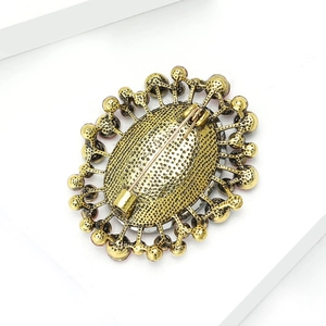 Detailed close-up of vintage gold alloy brooch back with textured finish and pin