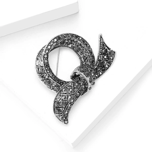 Vintage silver bow brooch with black rhinestones on a white background display