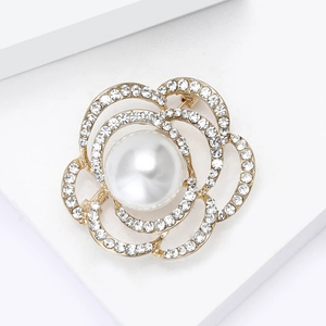 Vue détaillée de la broche camélia évidée avec perle et strass sur socle blanc