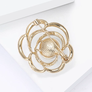 Vue arrière détaillée d'une broche fleur dorée avec pétales ajourés et fermoir de sûreté