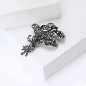 Macro shot of orchid bouquet brooch with black rhinestones on vintage silver metal
