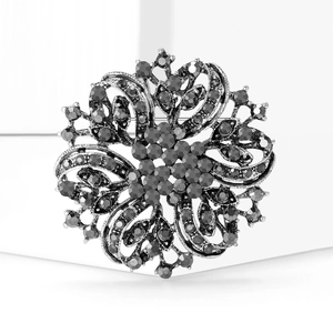 Vintage silver hollow floral brooch set with grey rhinestones on a white pedestal