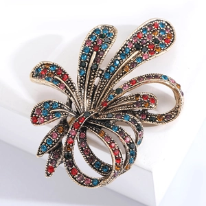 Close-up of vintage flower brooch with multi-colored rhinestones on a white stand