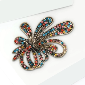 Detailed macro view of vintage gold flower brooch with multi-colored rhinestones