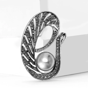 Broche plume vintage argentée avec perles gris foncé et strass sur décor blanc