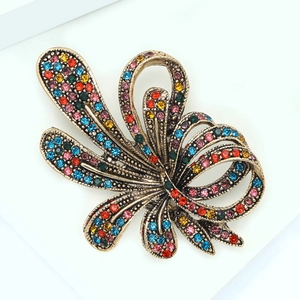 Macro detail of luxury vintage bow brooch with colorful rhinestones on gold alloy base