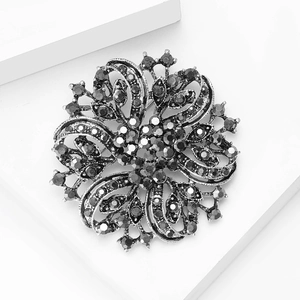 Macro detail of luxury vintage floral brooch with gray crystals on white geometric stand