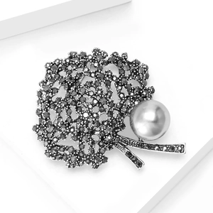 Vintage gunmetal tree brooch featuring black rhinestones and a large silver-grey pearl