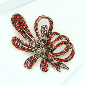 Macro detail of luxury vintage brooch with red rhinestones and golden ribbon design