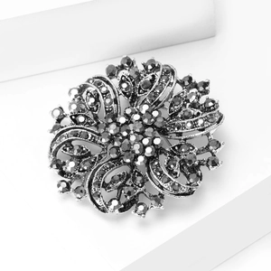 Macro shot of vintage style floral brooch featuring grey crystals and intricate filigree work