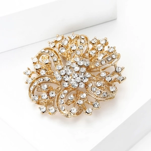 Macro view of a luxury gold floral brooch set with sparkling rhinestones on a white base