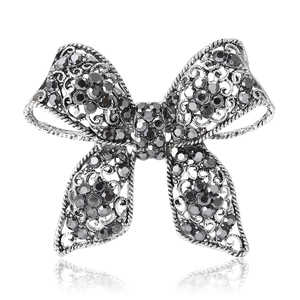 Vintage silver bow brooch with grey rhinestones and retro hollow patterns on white background