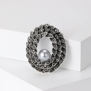 Vintage gunmetal wreath brooch featuring black crystals and a large grey pearl focal point