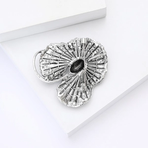Vue détaillée d'une broche vintage argentée avec texture en éventail et fermoir épingle