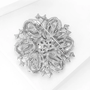 Close-up of vintage silver floral brooch with intricate hollow metalwork and pin clasp